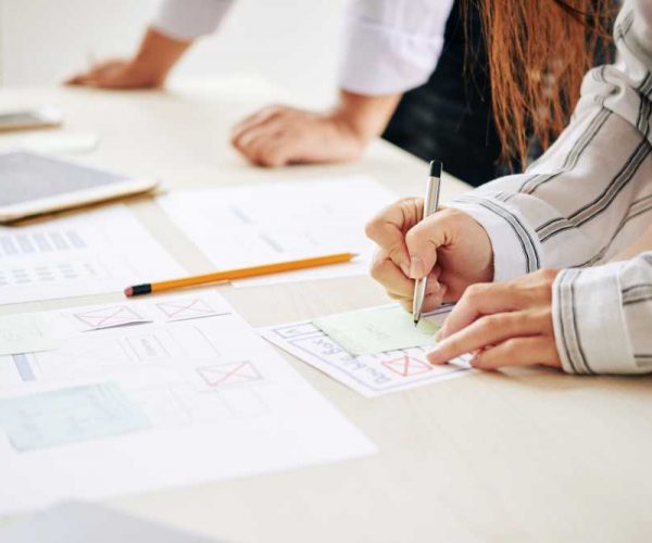Colleagues creating new web design Crop shot of woman taking notes on sticker while working with man in team at table creating modern design